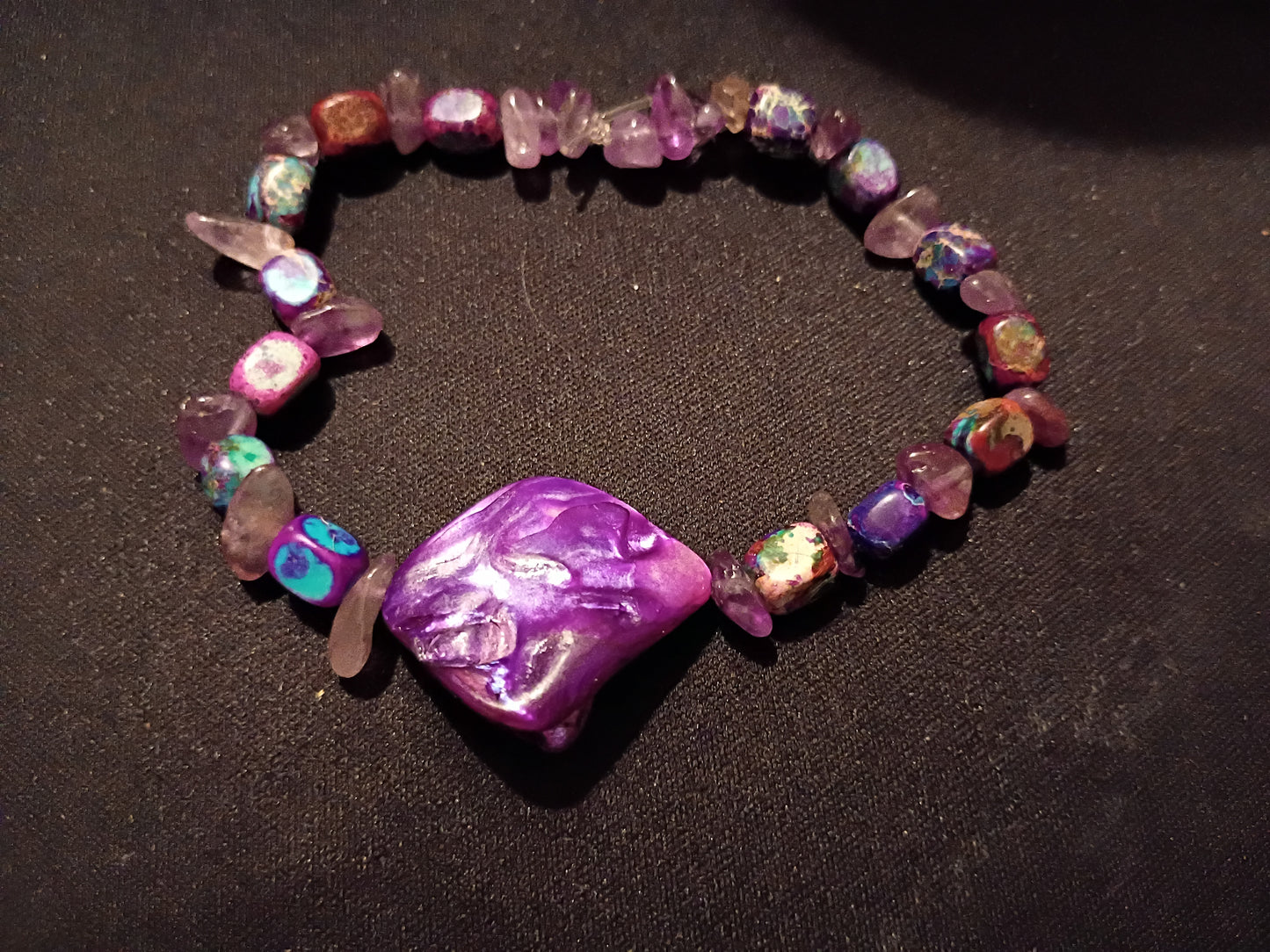 Praise Yahweh bracelet with purple and multicolored beads on a dark background